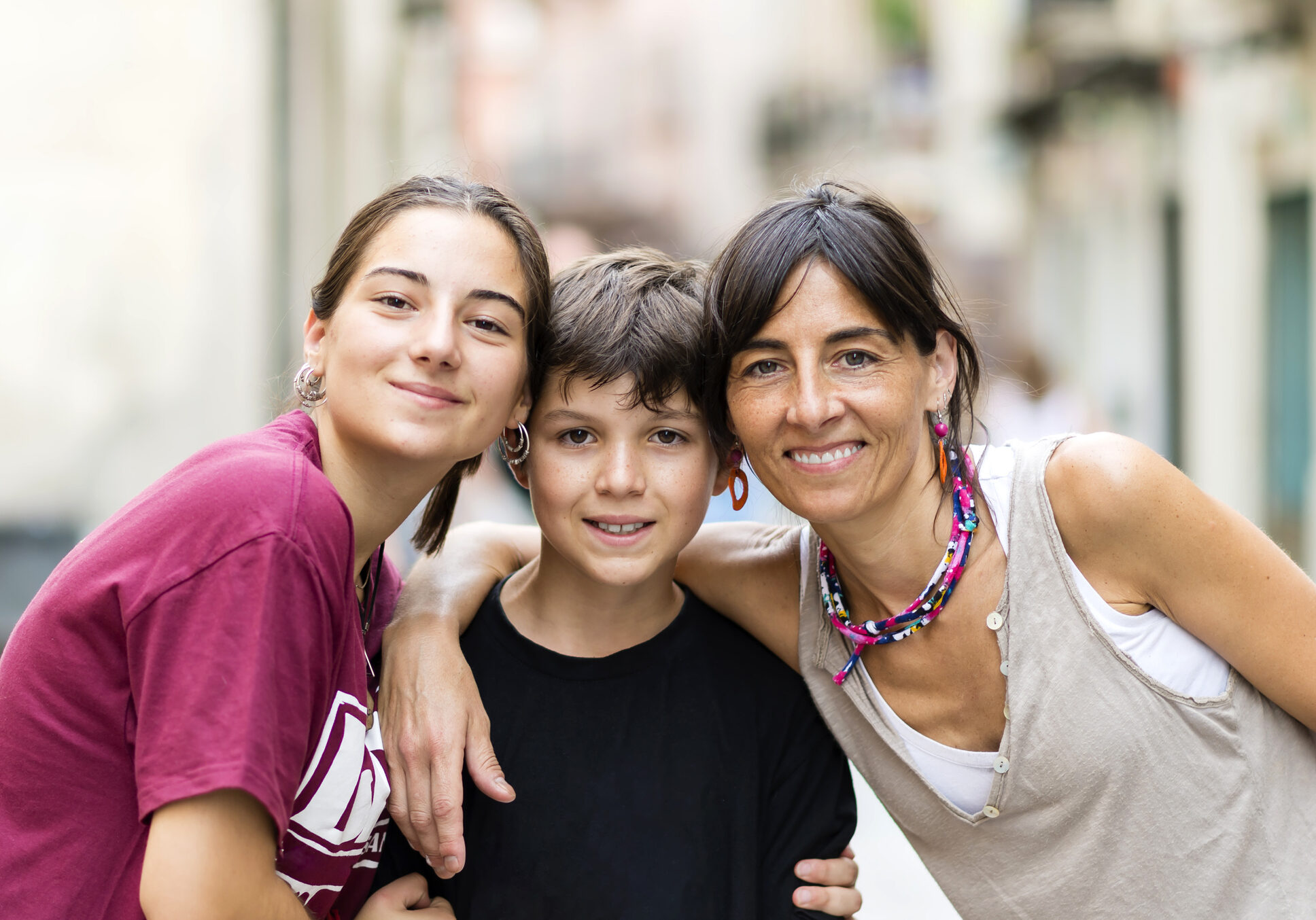 Portrait of 3 nice lovely cheerful affectionate people mom teen daughter and little son embracing outside sunny day