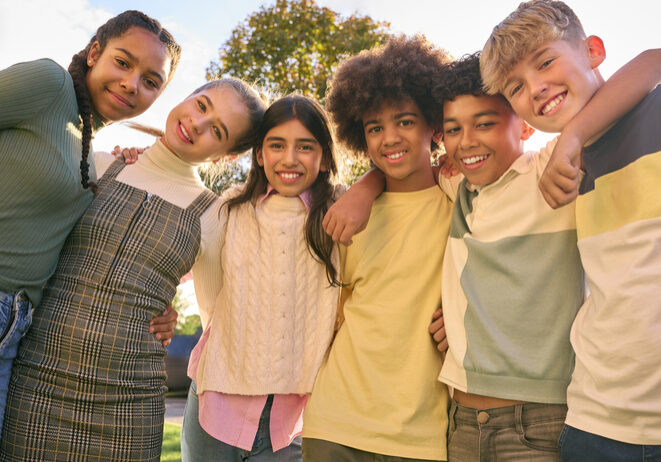 Portrait Showing Class Of Secondary Or High School Pupils Standing Outside School Building Hugging